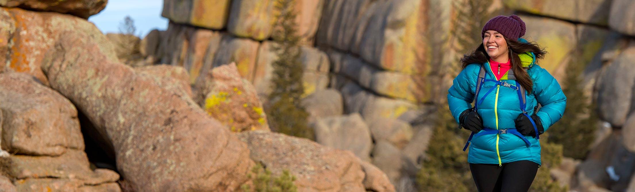 A person hiking wearing a blue winter jacker and a purple knit hat.