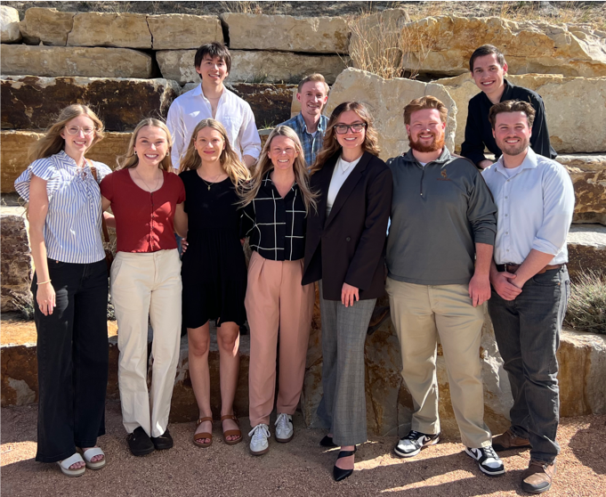 A group of people standing in-front of a stone formation and smiling at the camera.