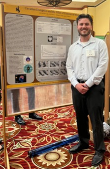 A man standing next to a research poster.