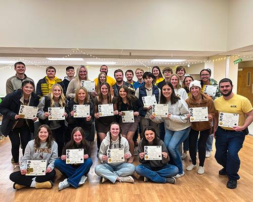 A large group of students holding up certificates and smiling at the camera.