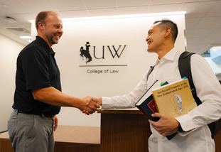 A new UW law students shakes hands with his advisor.
