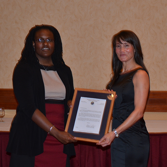 Laurene Rogers accepting a plaque from Professor Bridgeman