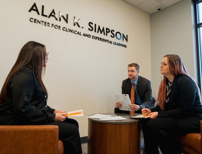 Three UW law students sit at a table examining documents.
