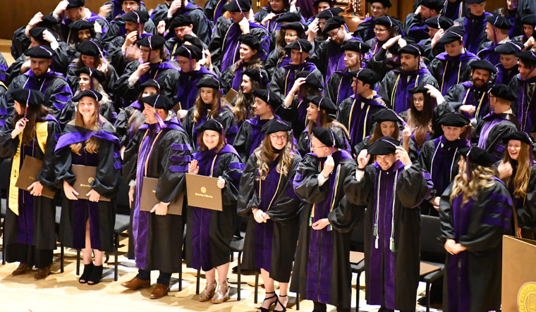 Graduating students in robes on stage