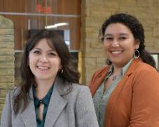 Two women in suits smiling
