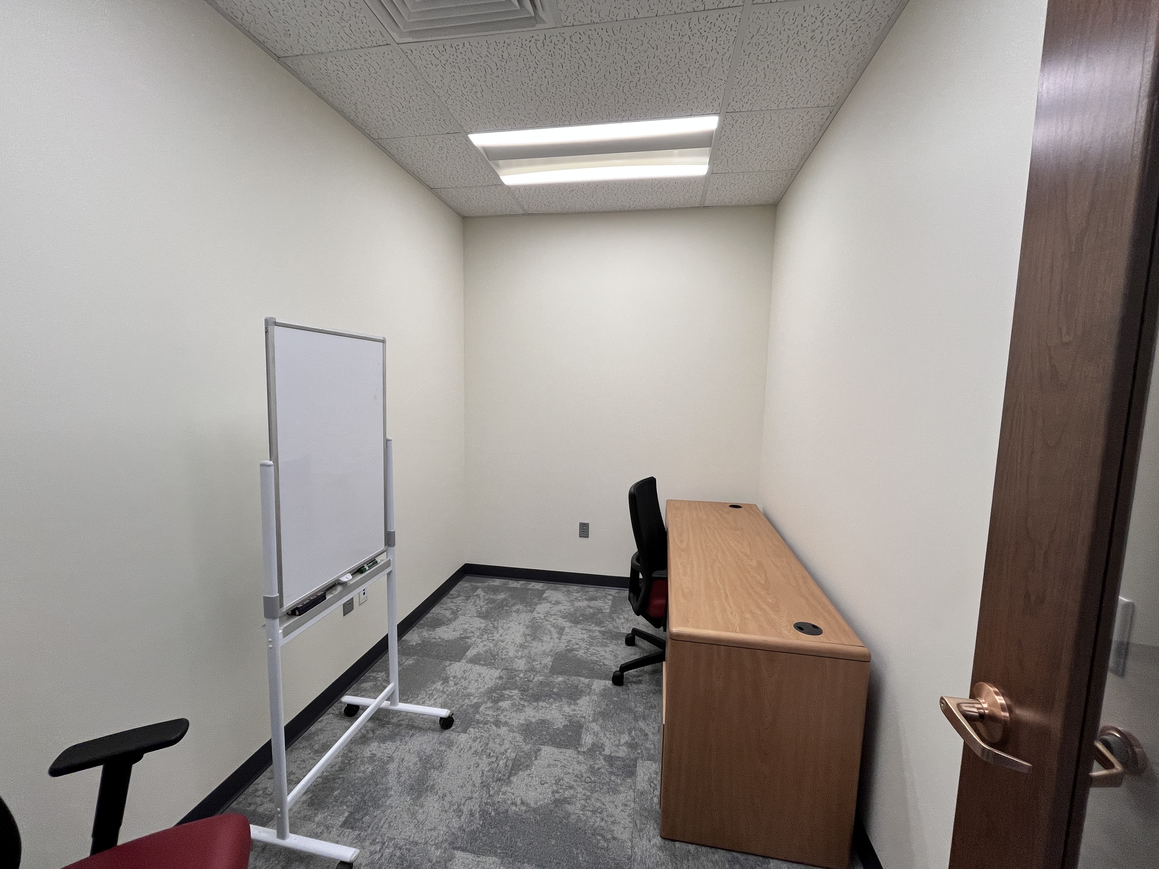 image of room 126, containing a table and two office chairs chairs on wheels