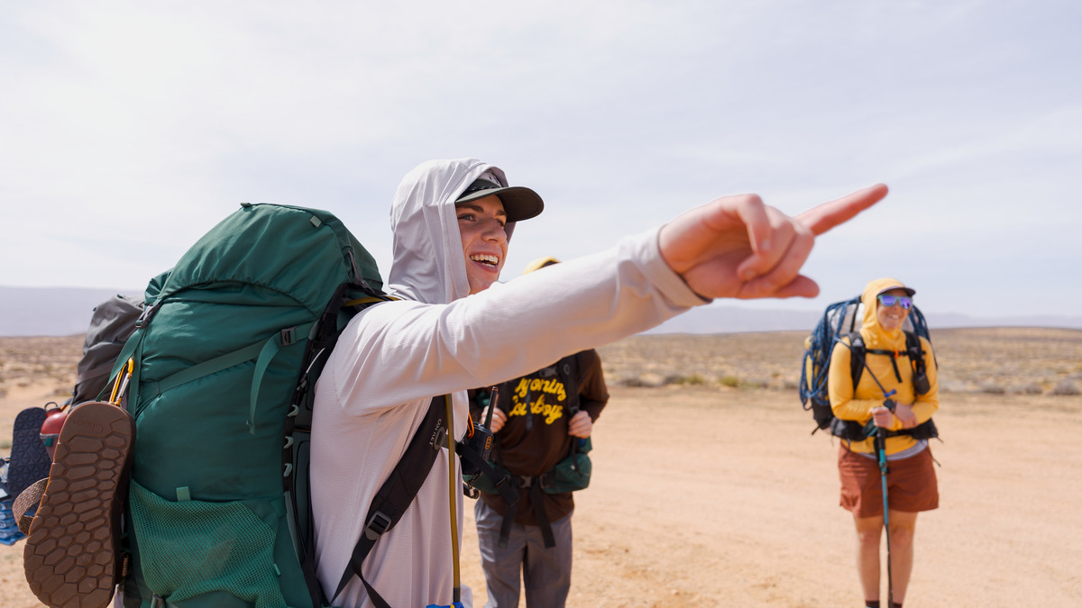 Three backpackers gather and one points to a spot to go.
