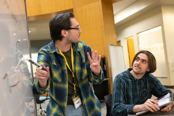 a tutor explains a concept to a student using a whiteboard.