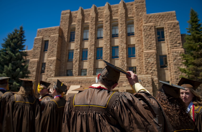 person in front of the Arts & Sciences building in cap and gown