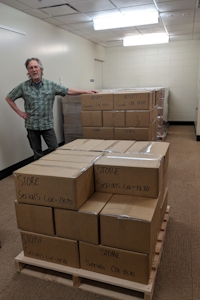pallets of boxes and Orrin standing next to them.