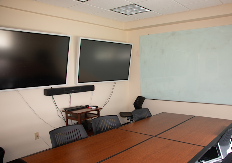 Study room featuring tables, two screens, spearker bar and white board