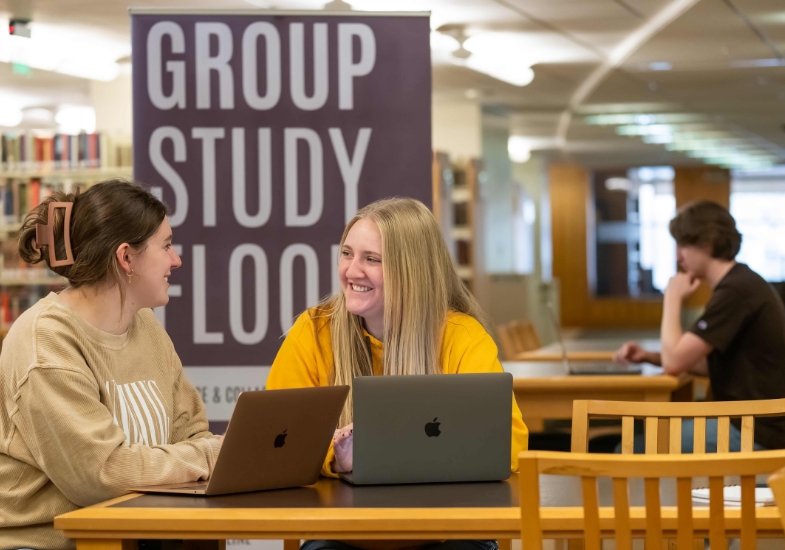 students sitting at a table chatting at a group study space in Coe Library