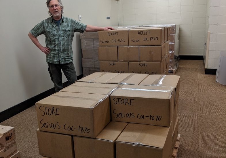 Orrin Koenig, Library Assistant, Senior stands next to boxes being prepped to be sent to WEST