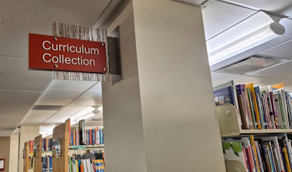 Curriculum Collection sign and books in stacks in Coe Library
