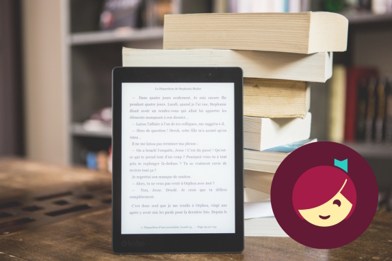 an ereader standing upright in front of a stack of books
