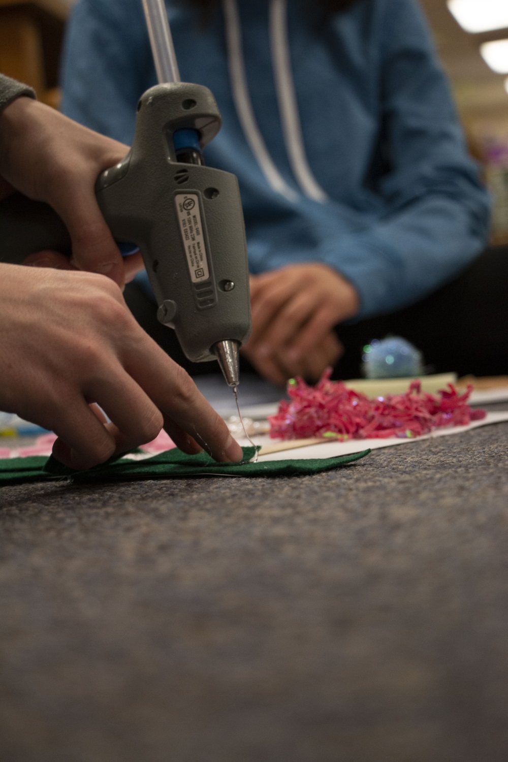 close up of student using a hot glue gun to make an accessible book
