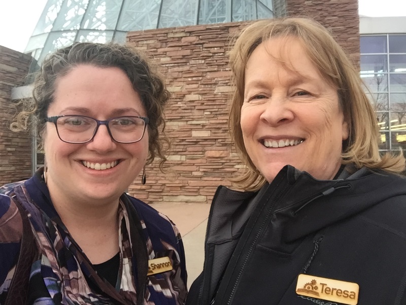 two women posing for photo in front of a building