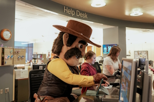 Pistol Pete assisting students at the Help Desk in Coe Library