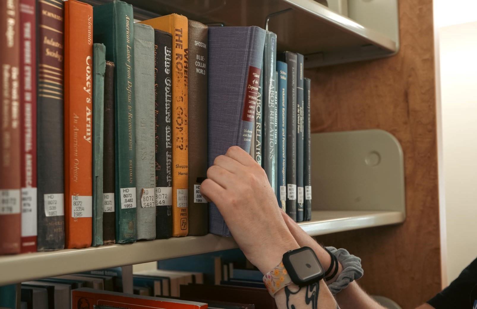 A book being pulled from a library shelf.