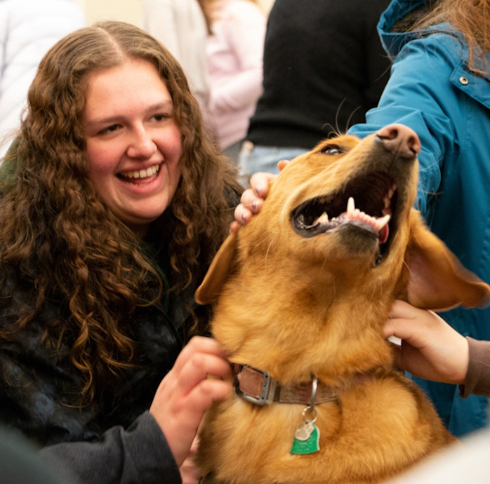 students petting a dog in Coe Library
