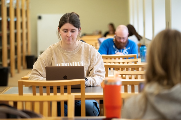 A student studies at a table in the Coe stacks.