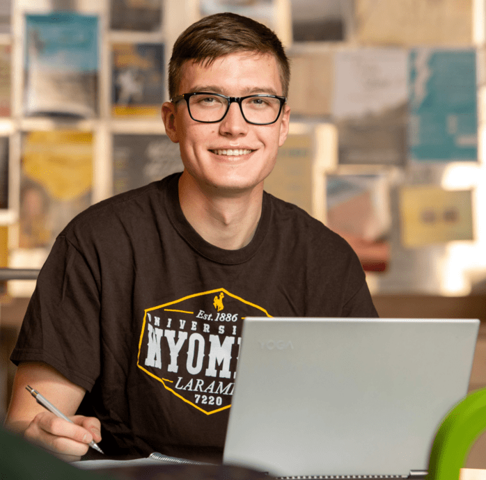 Student smiling while using laptop.