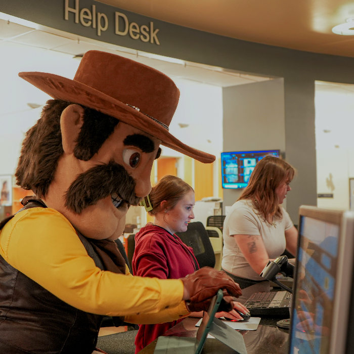 photograph of UW Cowboy Joe mascot working Coe Library checkout desk