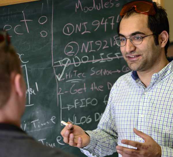 Instructor explaining class material with a student with a blackboard behind them