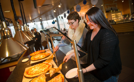 Two people serve themselves pizza in the UW dining hall.
