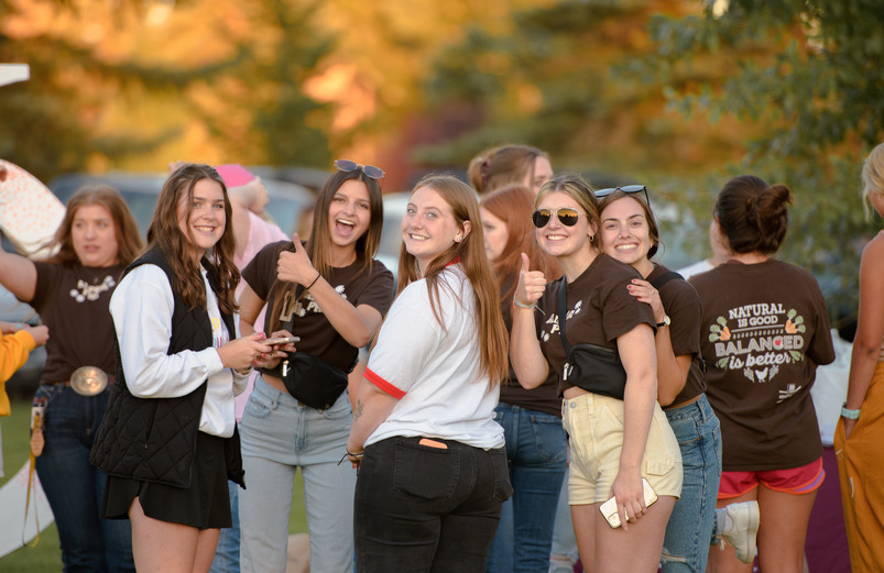 A group of students smile and give the camera a "thumbs up"