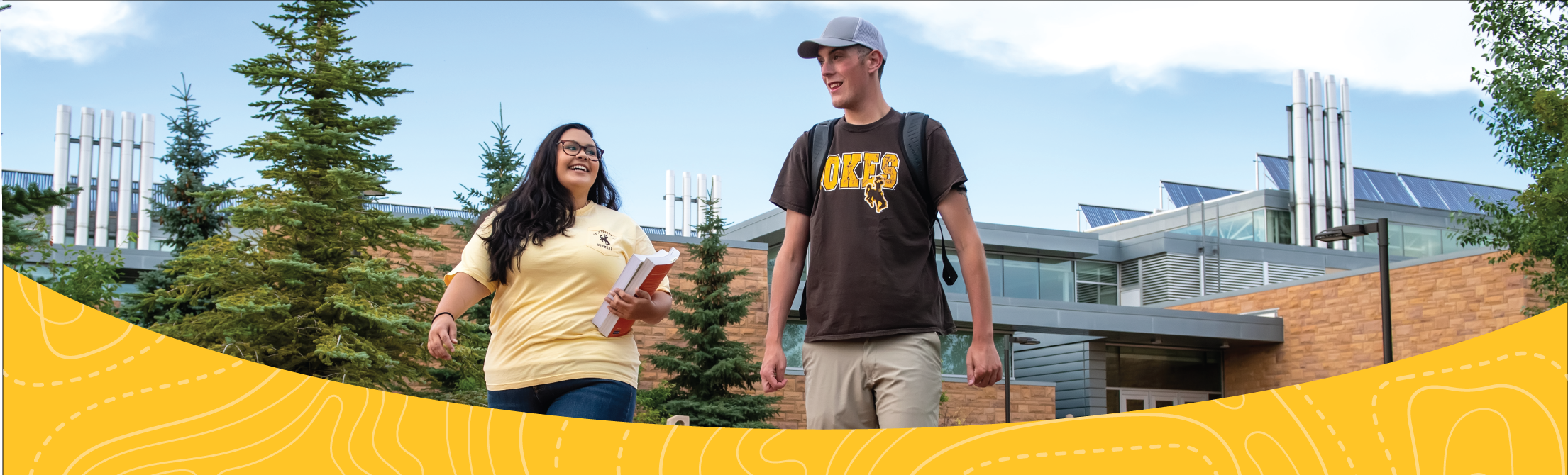 male and female student walking outdoors smiling at one another