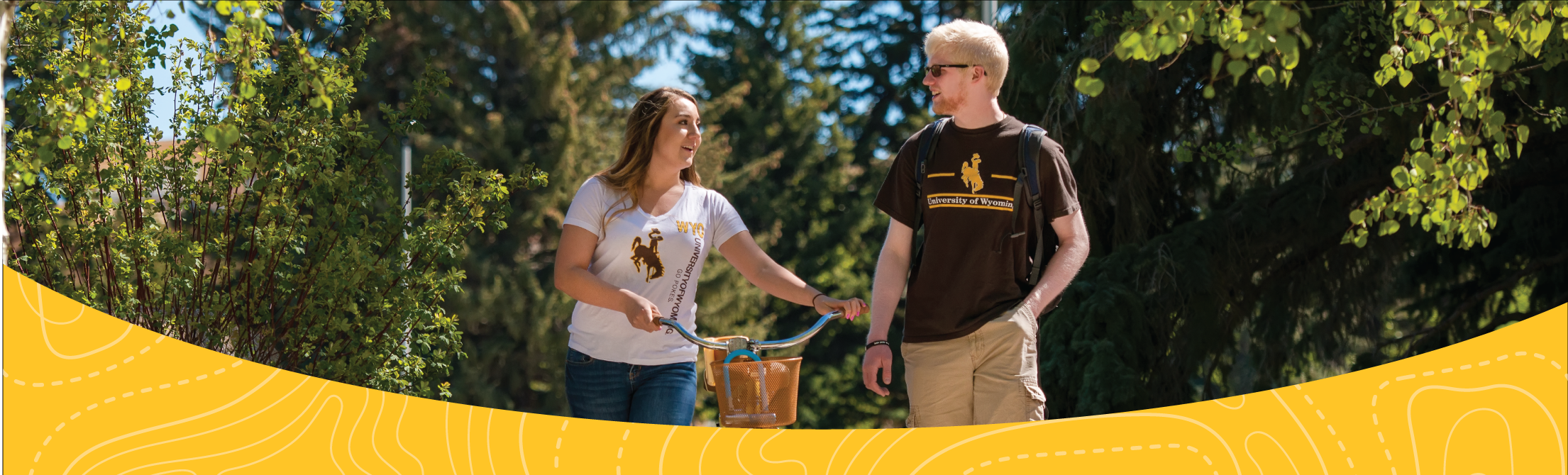 male and female student walking through prexy's pasture with a bike