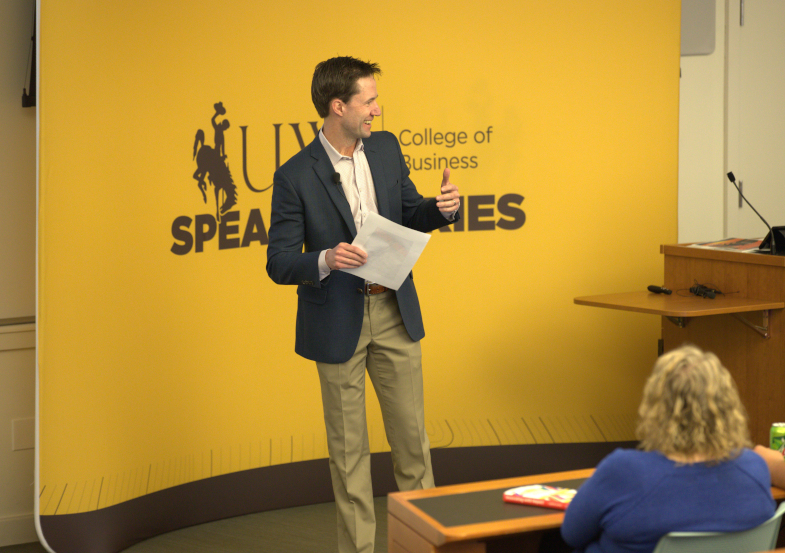 A speaker standing in front of an Executive Speaker Series sign speaking to the audience