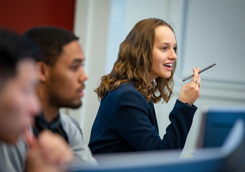 MBA student sitting in class and speaking at her desk