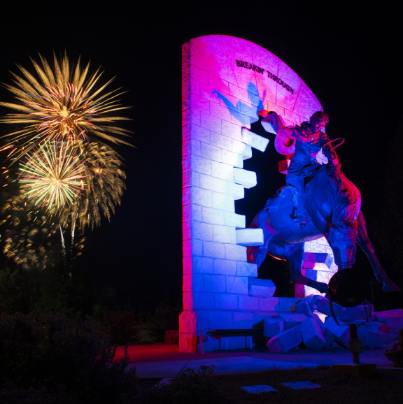 Nighttime photo of fireworks behind the Breaking Grounds statue
