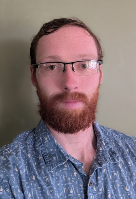 candid photo of McGinley Zastrow in a blue patterned button up shirt against a neutral background.