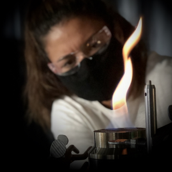 image of a female engineering grad students viewing a flame in a laboratory setting