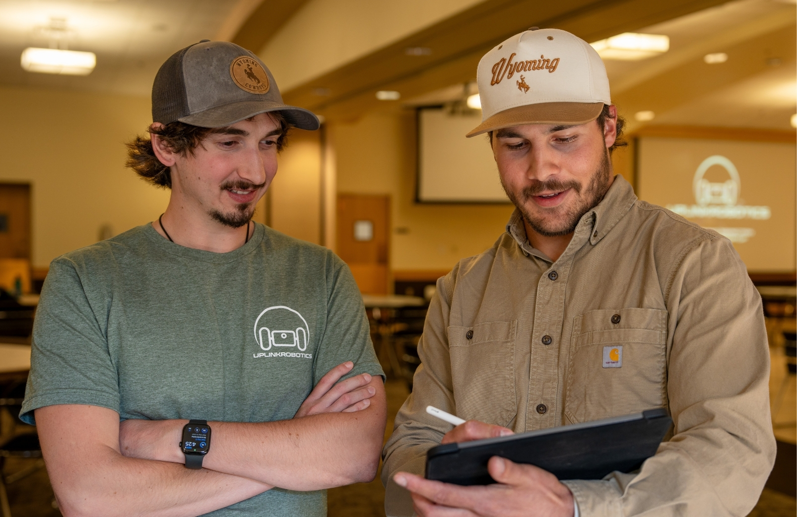 Senior design students shows his project using a tablet to the project sponsor, and UW electrical engineering Alumus, CEO, and co-founder of Uplink Robotics, Christian Bitzas.