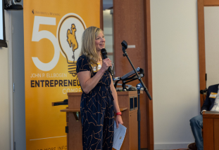 speaker in front of a the 50k challenge poster