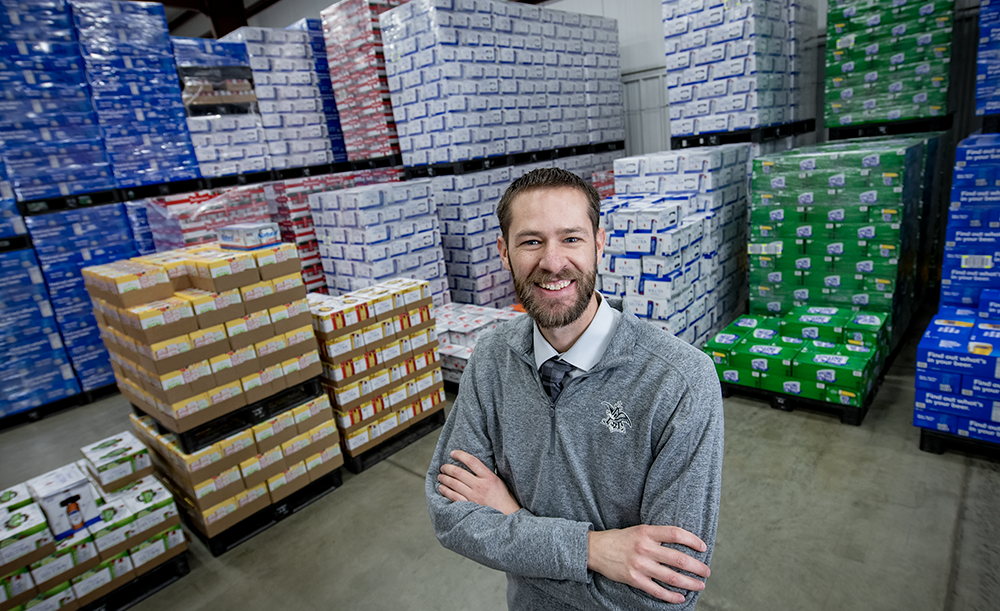 Photo of worker standing in front of pallets of beverages