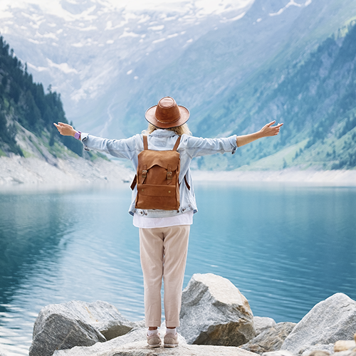 Person overlooking lake with arms out