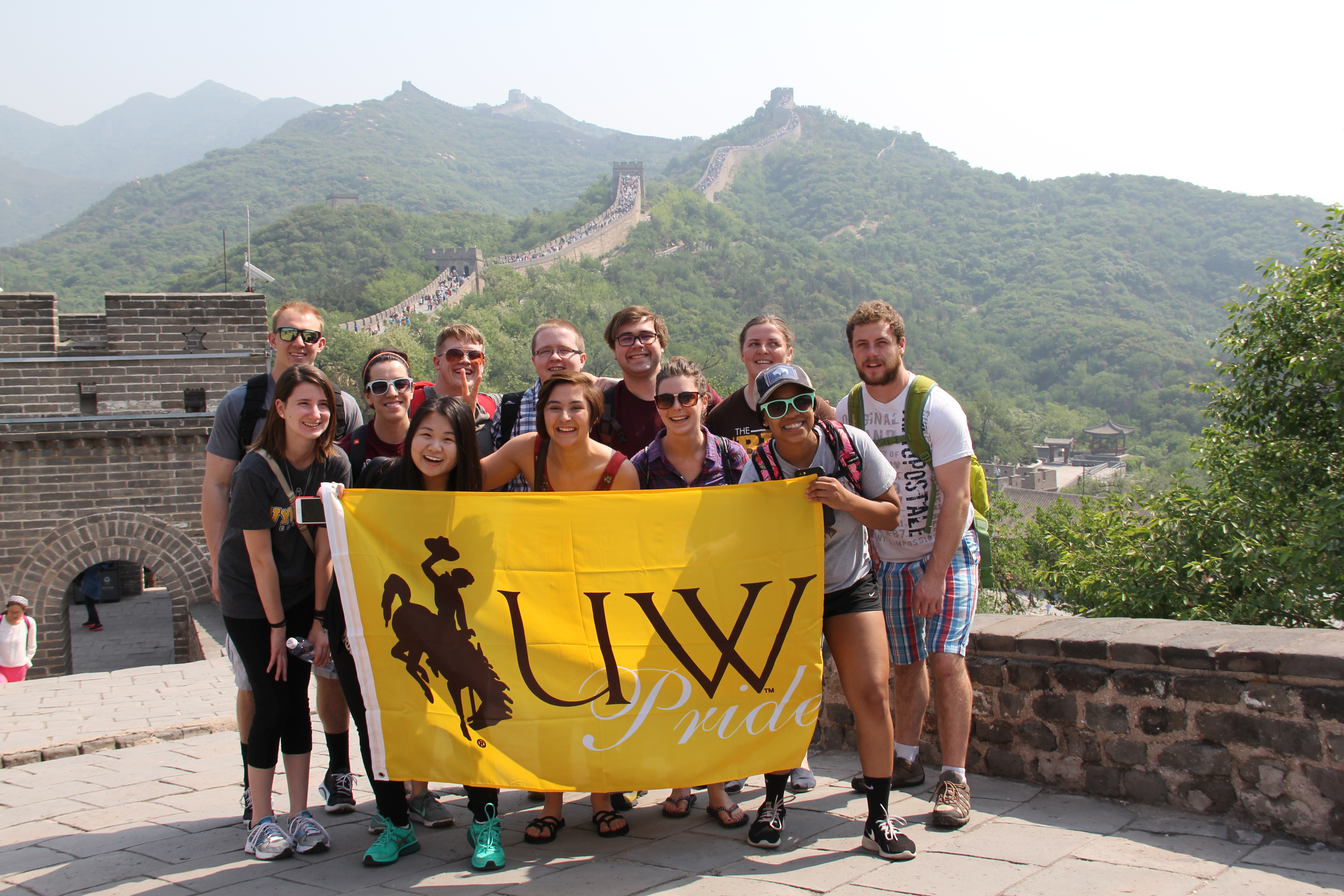 group of students at the great wall of china holding a university of Wyoming flag 
