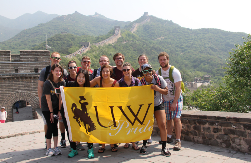 Students hold a UW banner while standing on the Great Wall of China.