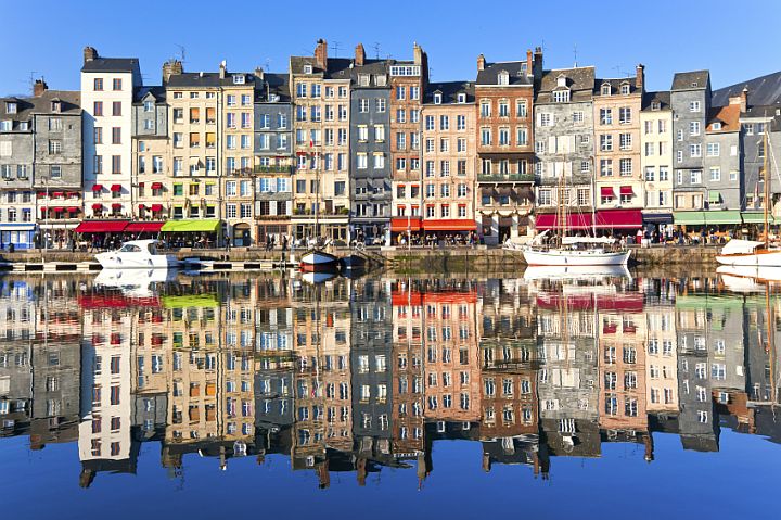 colorful multistory buildings being reflected by a river in front