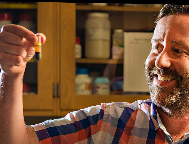 Man holding a vile in a biology lab.