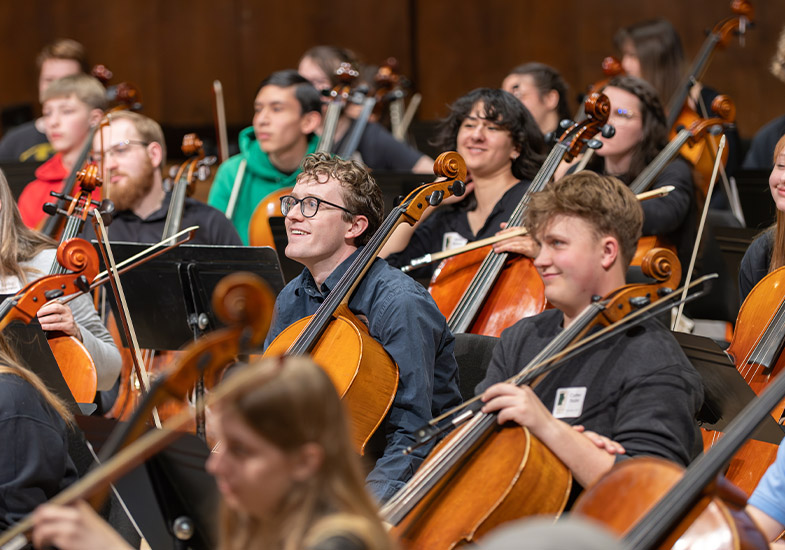 Students listening, holding string instruments