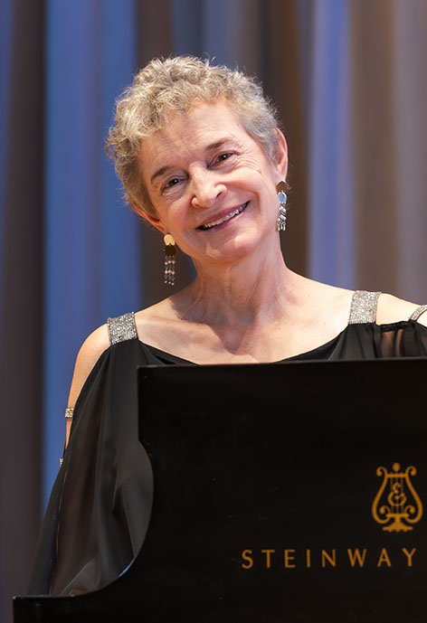 Picture of woman sitting at a piano smiling