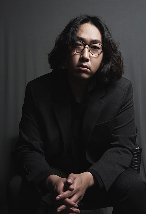 Picture of man sitting in dim lighting.