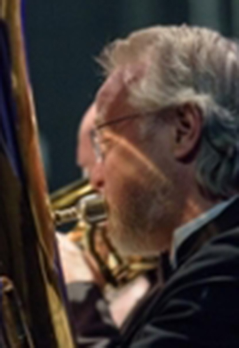 Photo of Alan Harvey from behind while playing the tuba