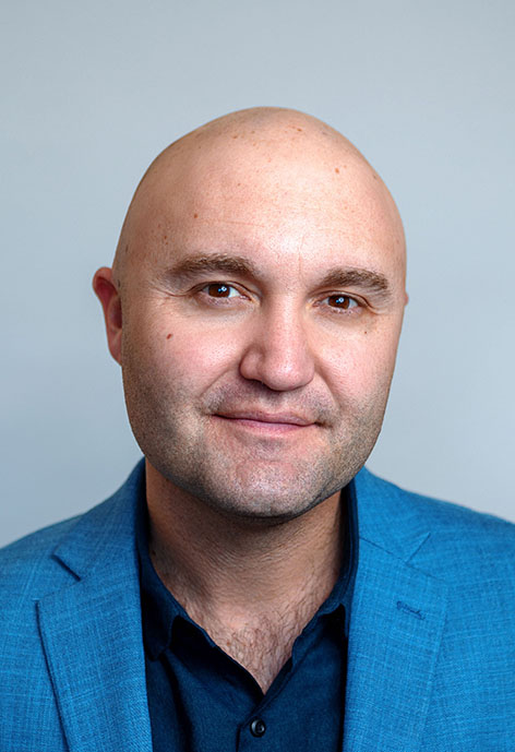 Photo of Ben Markley smiling in a blue suit